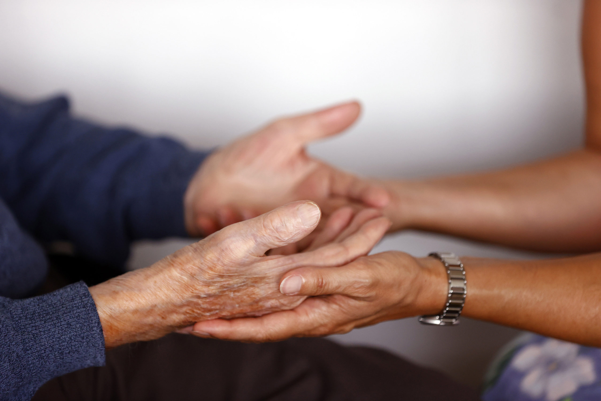 Retirment home. Close up of care assistants hand reassuring senior man.
