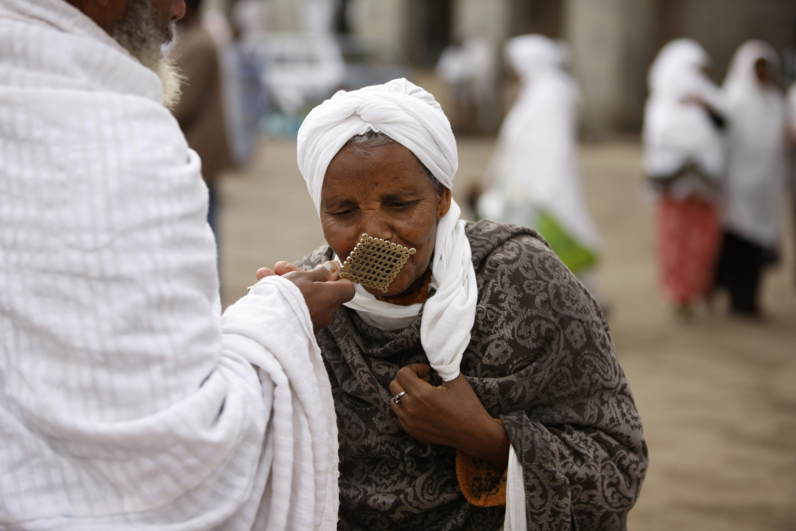 Woman kissing a priest's cross after mass in Saint Urael church